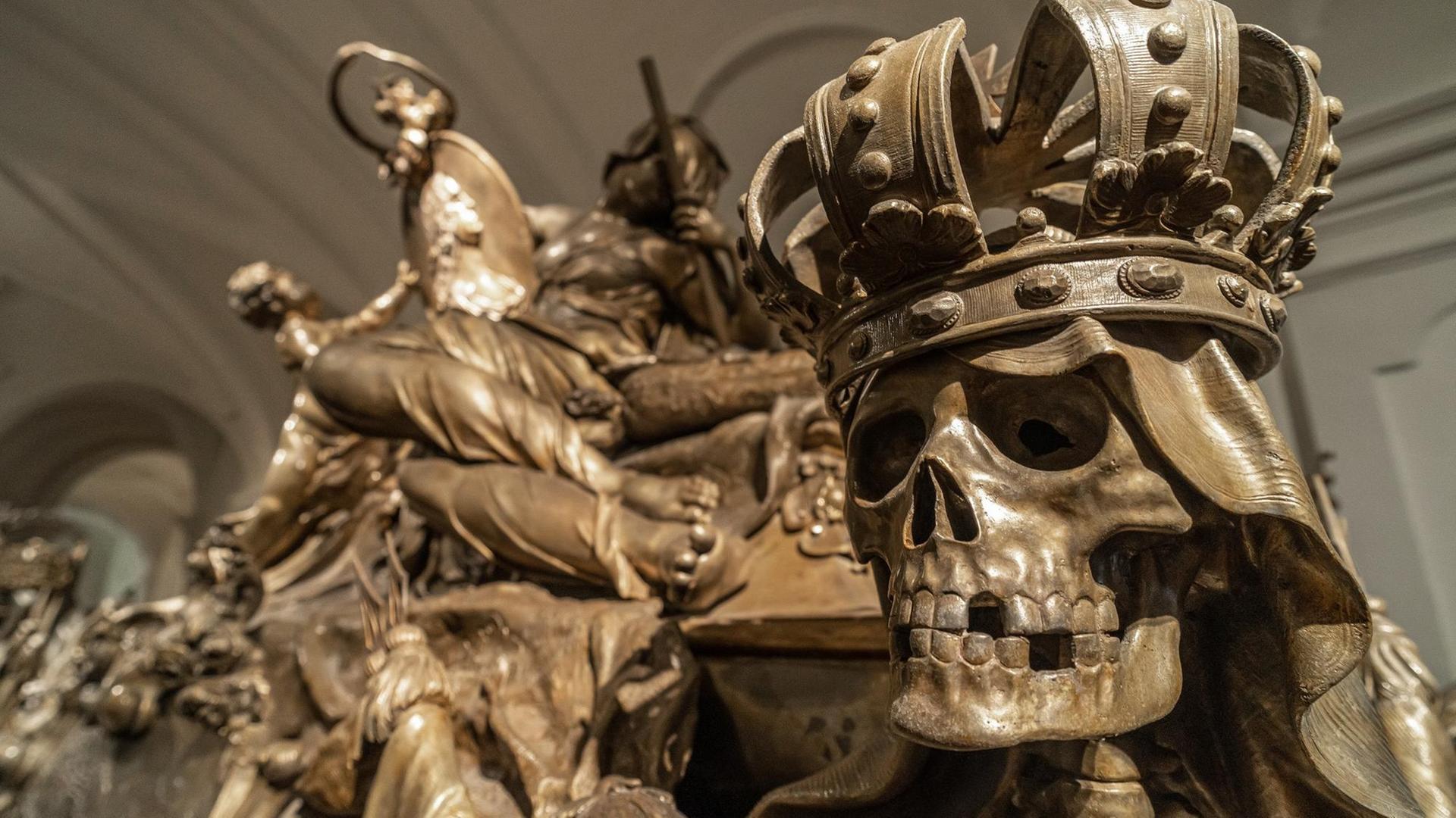 Ein metallener Totenkopf mit Krone und fehlenden Zähnen.