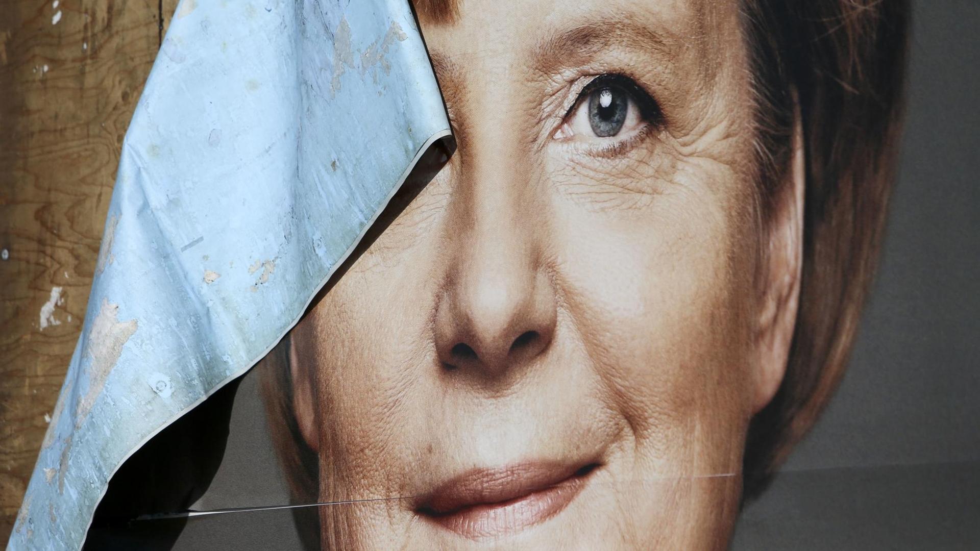 Das Bild zeigt ein kaputtes Wahlplakat von Angela Merkel.