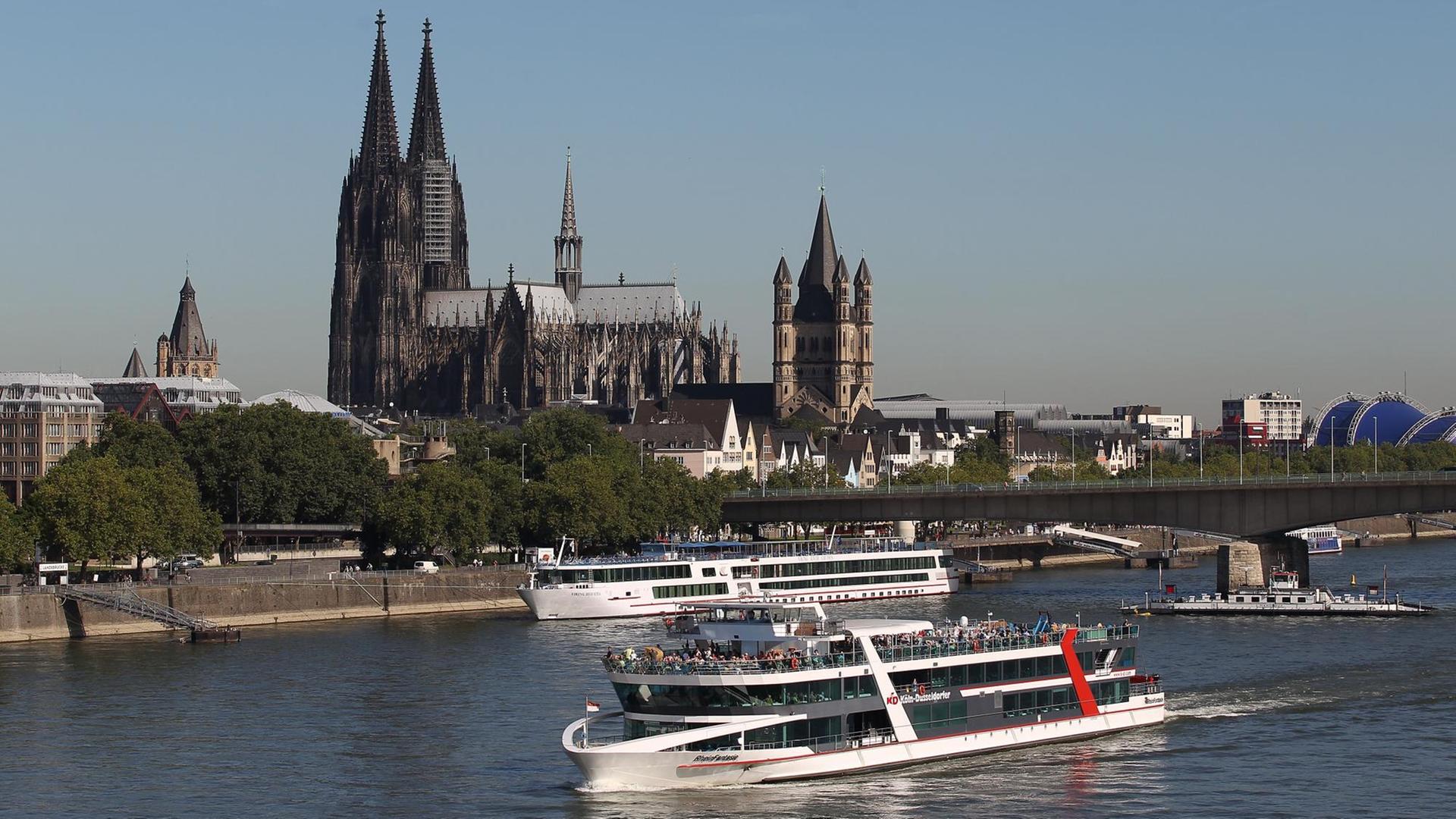 Ein Schiff fährt in Köln am Dom vorbei über den Rhein.
