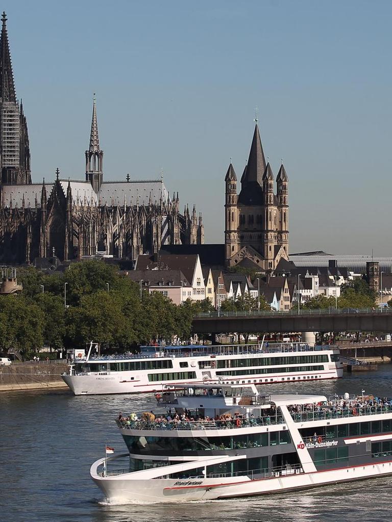 Ein Schiff fährt in Köln am Dom vorbei über den Rhein.