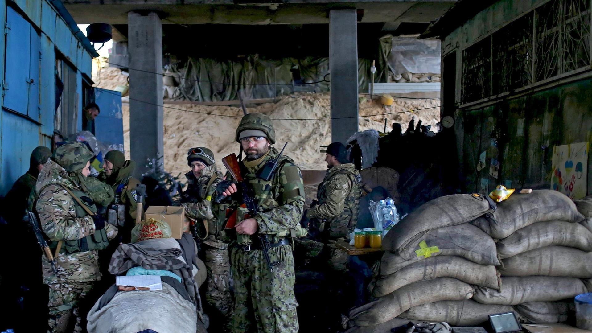 Eine Gruppe von ukrainischen Soldaten steht bewaffnet und mit Sandsäcken gesichert unter einer Brücke.