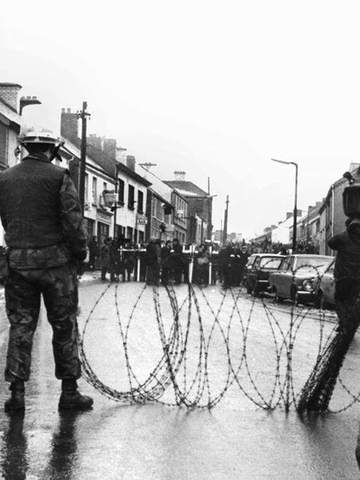 Britische Soldaten haben am 2. Februar 1972 in der nordirischen Stadt Dunsgiven mit Stacheldraht eine Straße vor nahenden Demonstranten gesperrt.