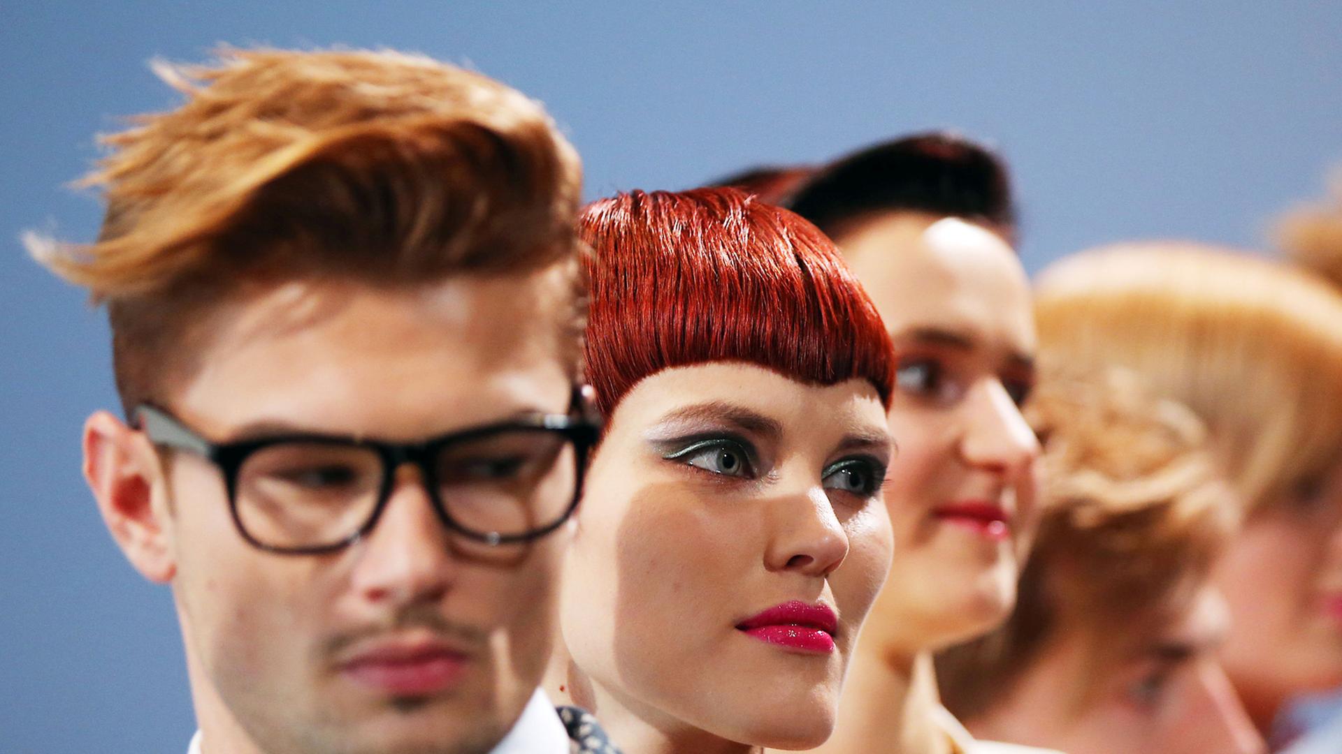 Models gehen mit neuen Frisuren über einen Laufsteg.