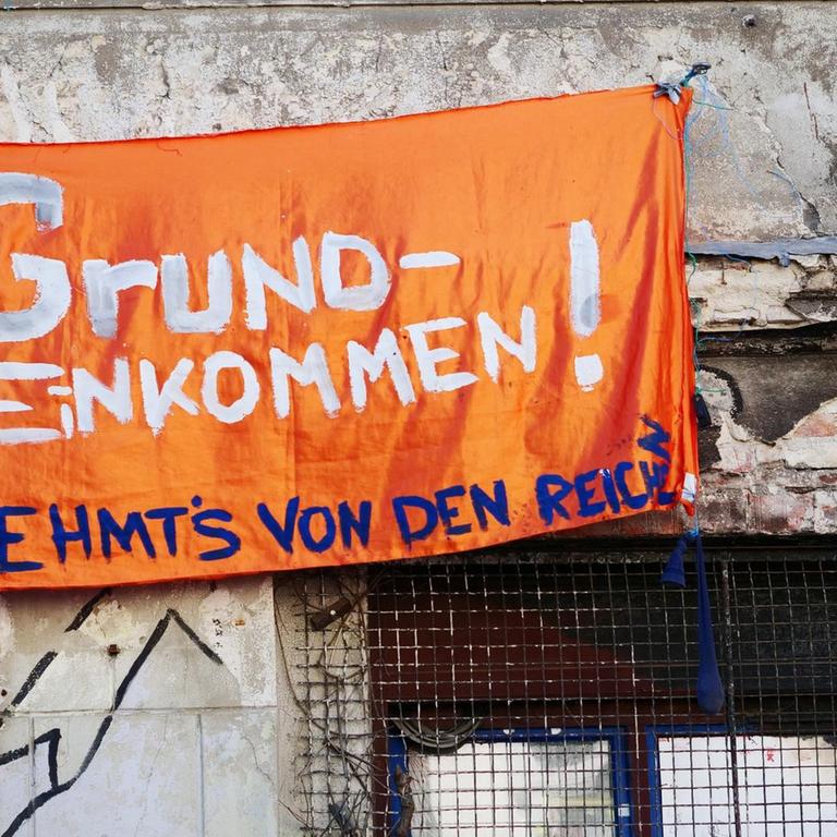 Ein Transparent mit der Aufschrift "Grundeinkommen! Nehmt's von den Reichen" hänft in Berlin an einem unsanierten und besetzten Haus in der Linienstrasse im Bezirk Mitte.