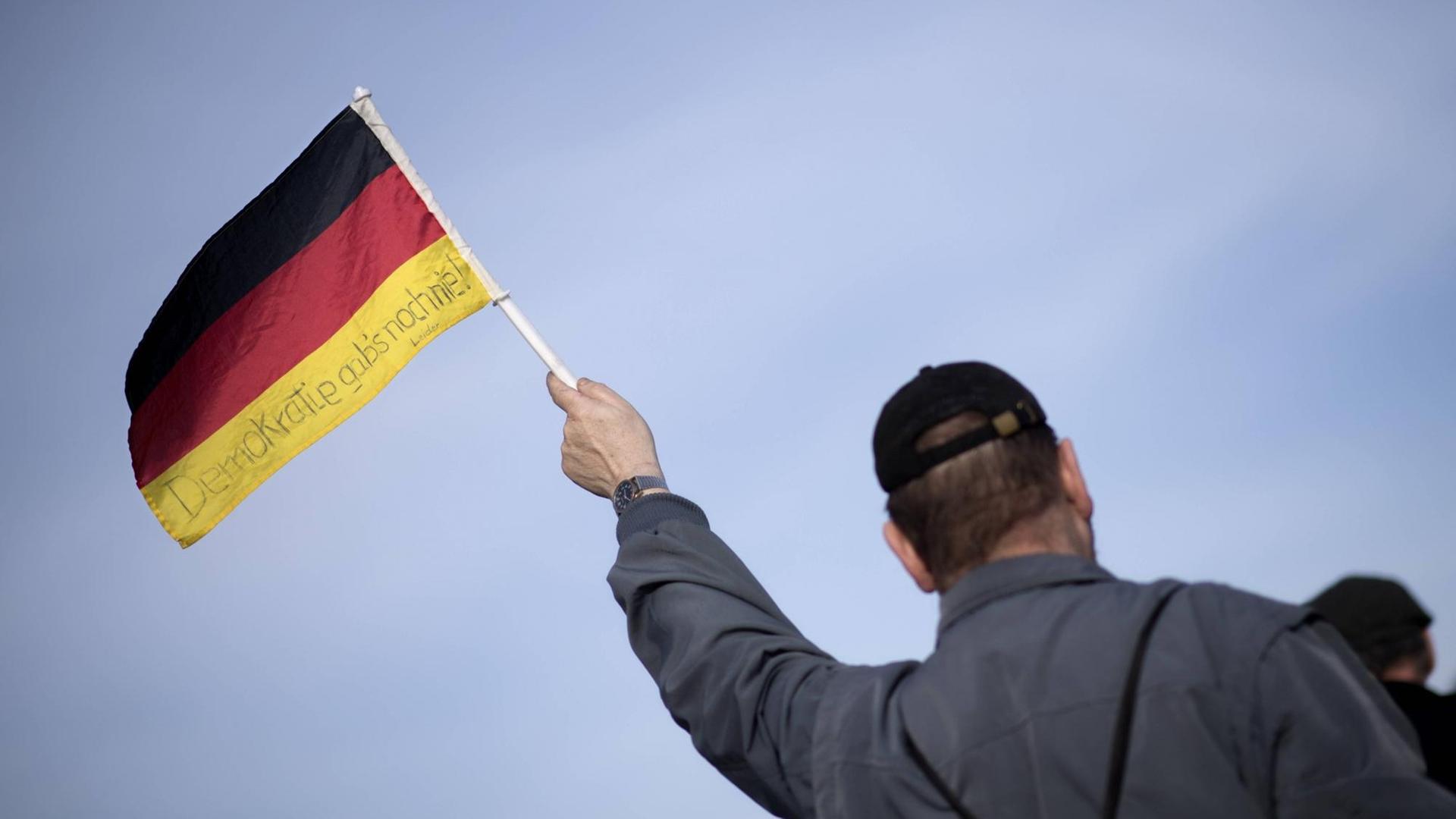 Ein Demonstrant bei einer Demo rechter Gruppen in Berlin 2017 hält eine deutsche Fahne hoch