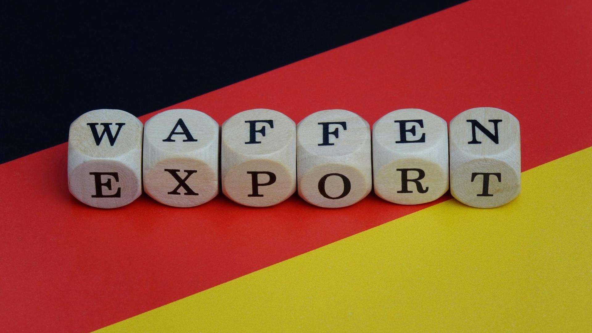 Auf einer Deutschlandfahne liegt mit Würfeln gelegt das Wort Waffenexport.
