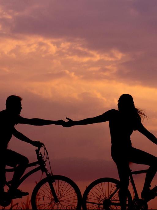 Ein Paar fährt bei Sonnenuntergang auf dem Fahrrad.