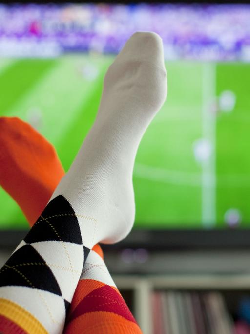 Ein junge Frau trägt am 13.06.2012 vor einem Fernseher in Köln während des EM-Spiels Dänemark gegen Portugal Socken in den Deutschlandfarben und in den Farben der Niederlande. Die deutsche Fußball-Nationalmannschaft trifft am Abend bei der EM auf die Niederlande.
