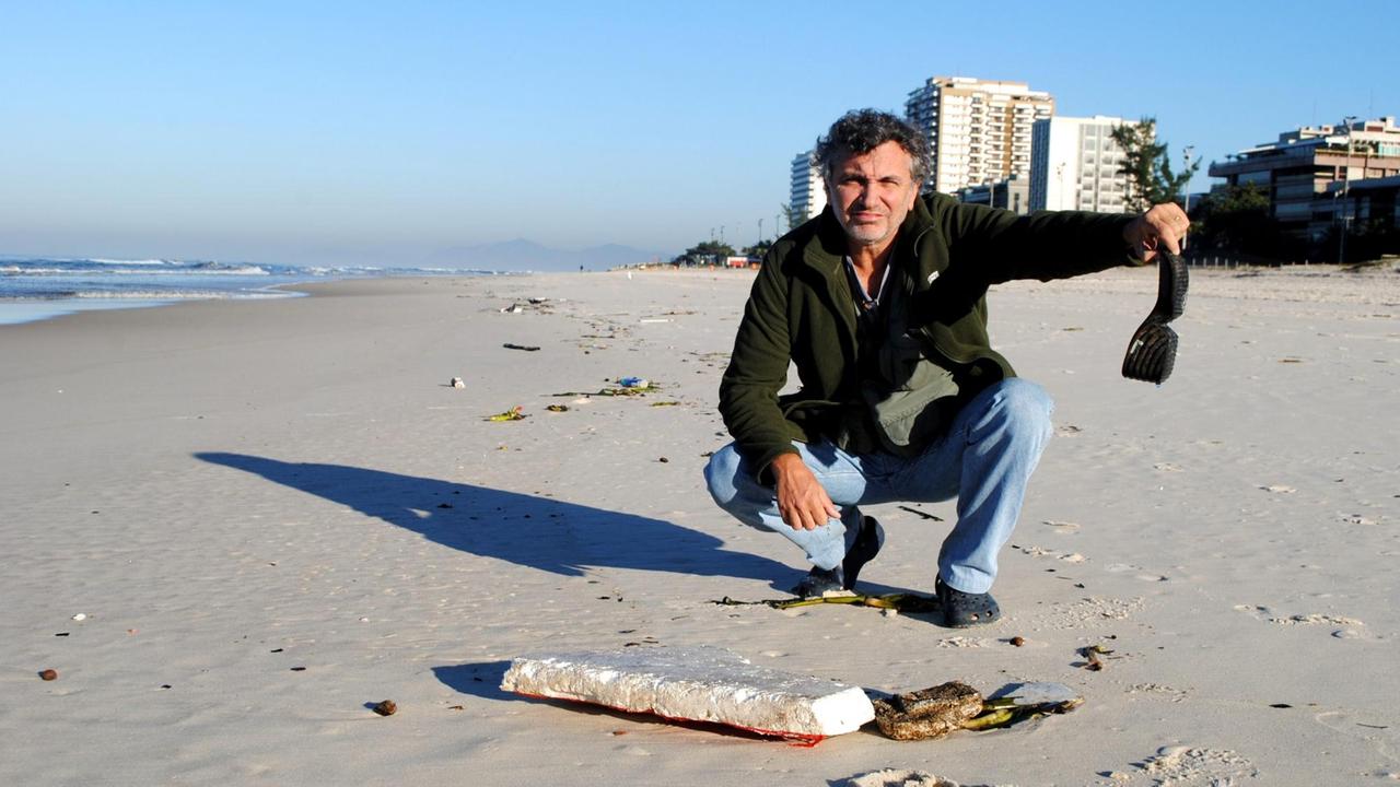 Mário Moscatelli im Morgengrauen an einem Strand, an den die Ebbe Müll abgespült hat.