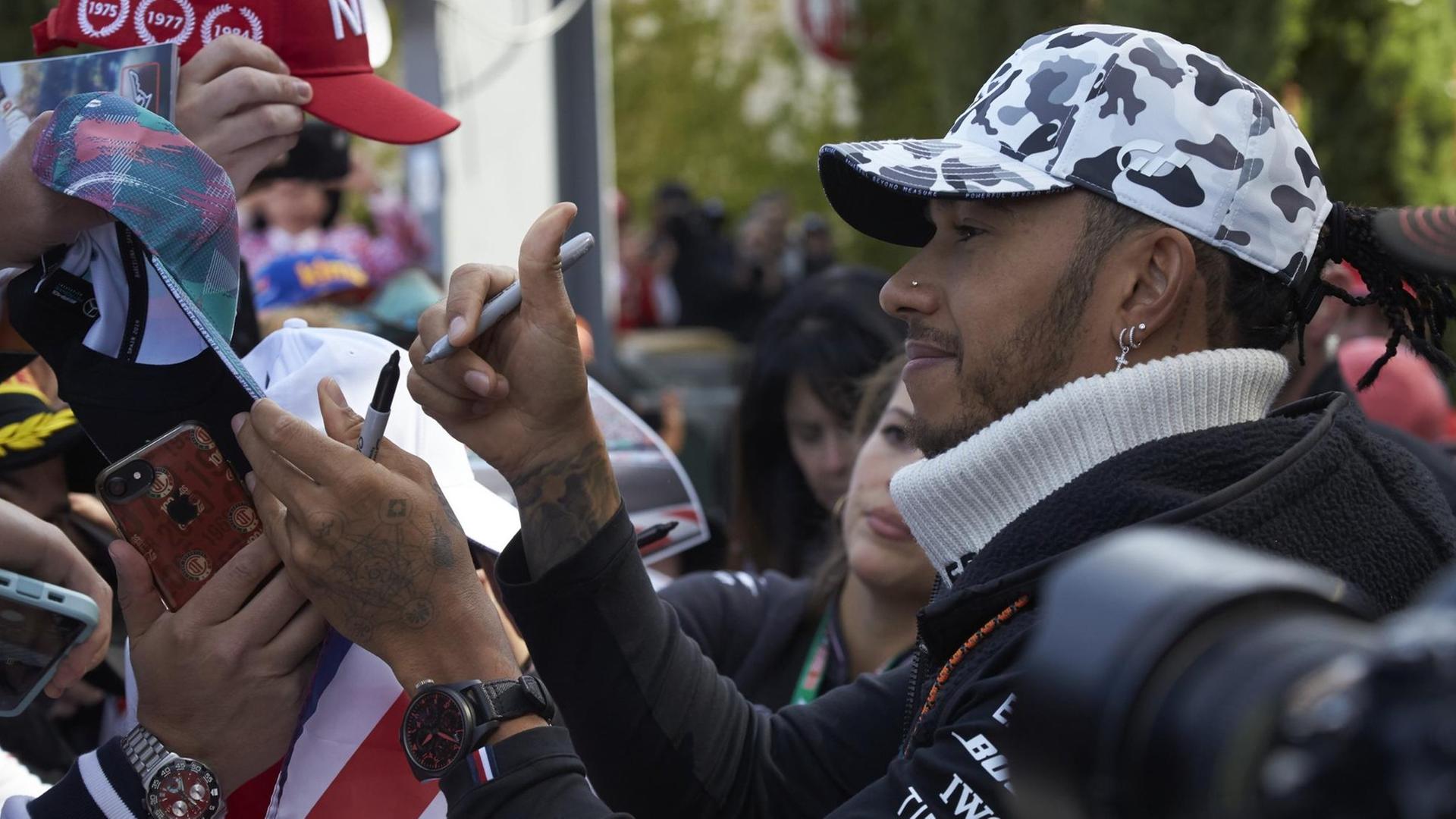Lewis Hamilton schreibt Autogramme.