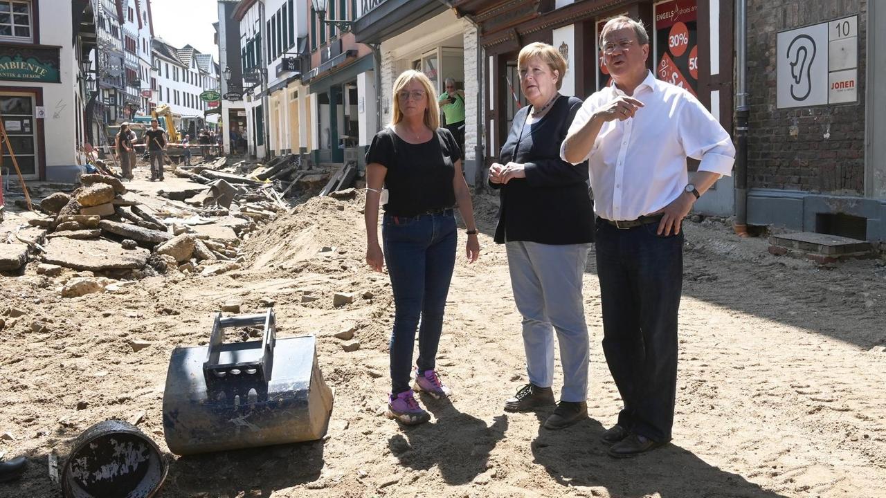 Bundeskanzlerin Angela Merkel steht mit NRW-Ministerpräsident Armin Laschet und der Bürgermeisterin von Bad-Münstereifel in einer zerstörten Straße Bundeskanzlerin Angela Merkel steht mit NRW-Ministerpräsident Armin Laschet und der Bürgermeisterin von Bad-Münstereifel in einer zerstörten Straße