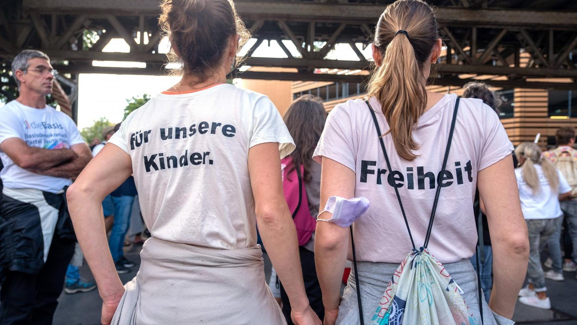 Aufnahme zweier Frauen von hinten. Beide tragen bedruckte T-Shirt mit der Aufschrift 'für unsere Kinder.' und 'Freiheit'. Aufnahme zweier Frauen von hinten. Beide tragen bedruckte T-Shirt mit der Aufschrift 'für unsere Kinder.' und 'Freiheit'.