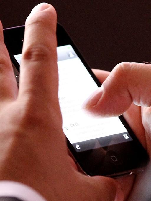 Ein Mann schaut auf das Display eines Smartphones.