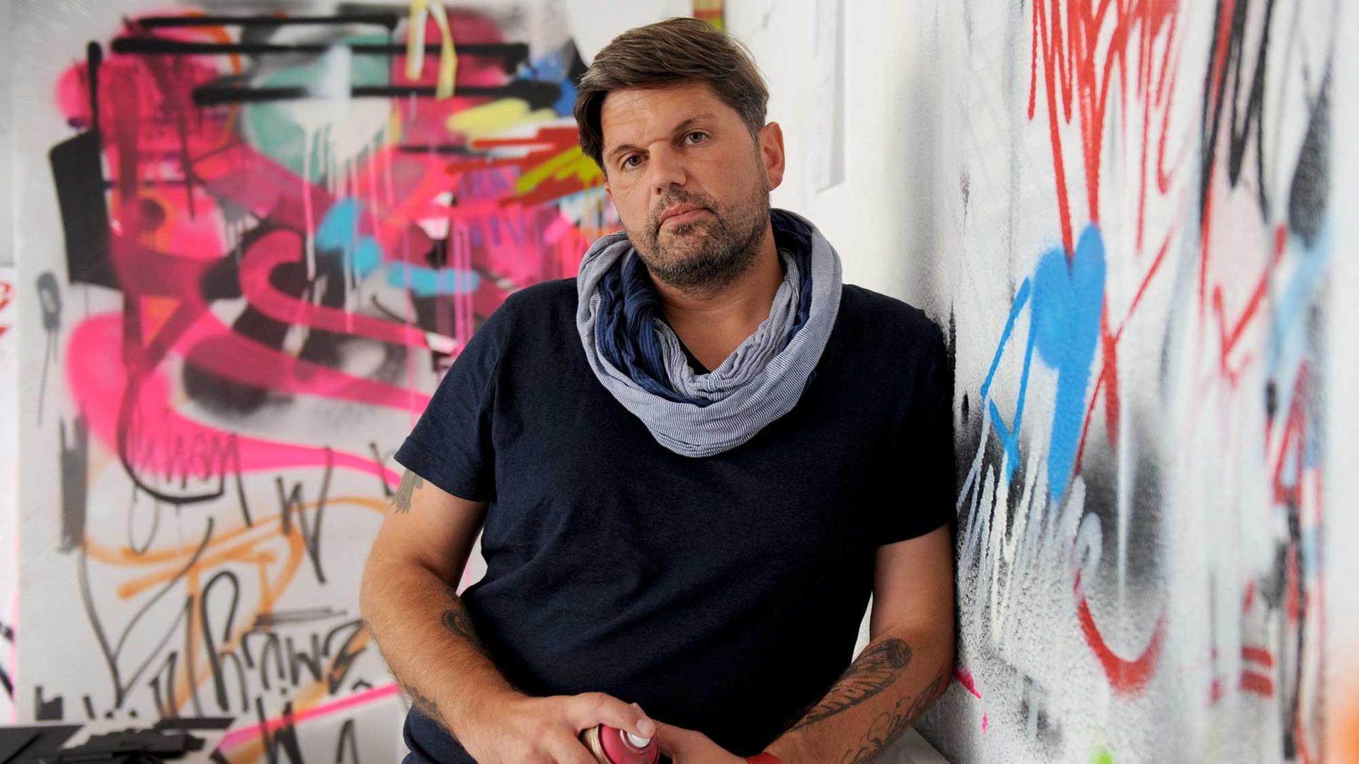 Der Graffiti-Künstler Markus Genesius lehnt am 28.08.2015 mit einer Sprühdose in den Händen an einer Wand seines Ateliers in Bremen. Einige seiner Werke hängen als Entwürfe auf Leinwänden an den Wänden. Genesius gehört zu den etablierten Graffiti-Künstlern, die international im Einsatz sind. Sein Künstlername lautet wow123.
