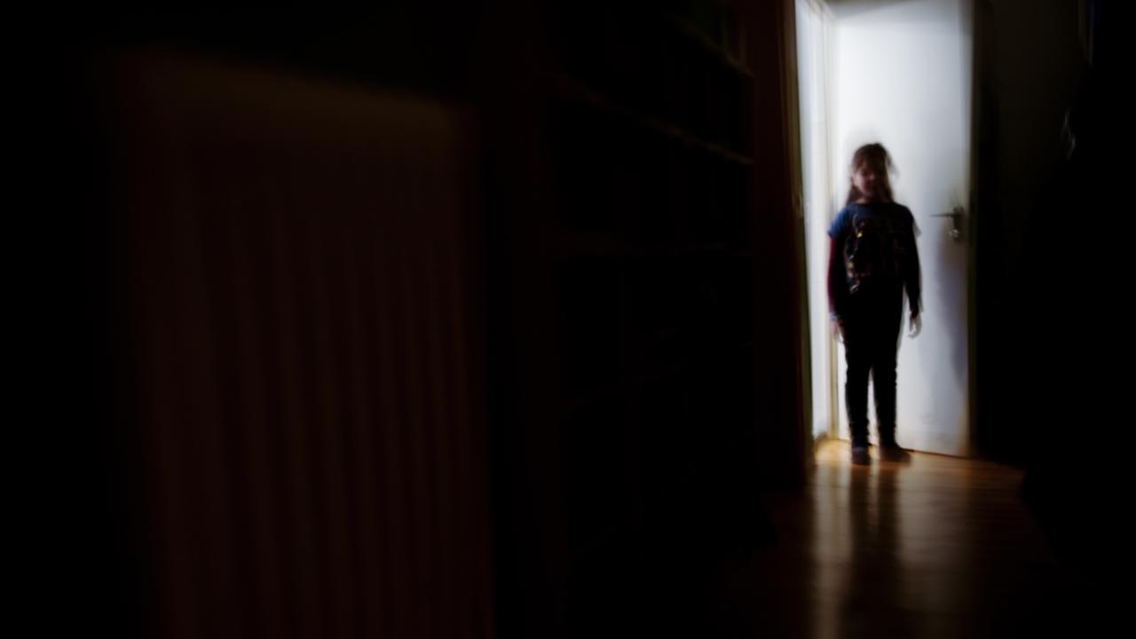 ILLUSTRATION - Ein junges Mädchen steht am 24.01.2014 in Berlin am Ende eines dunklen Flures (Aufnahme durch bewusste Bewegung bei längerer Belichtungszeit). Foto: Nicolas Armer/dpa