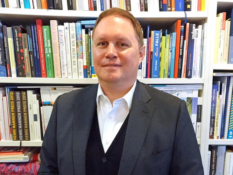 Hamburgs Kultursenator Carsten Brosda steht vor einem Bücherregal