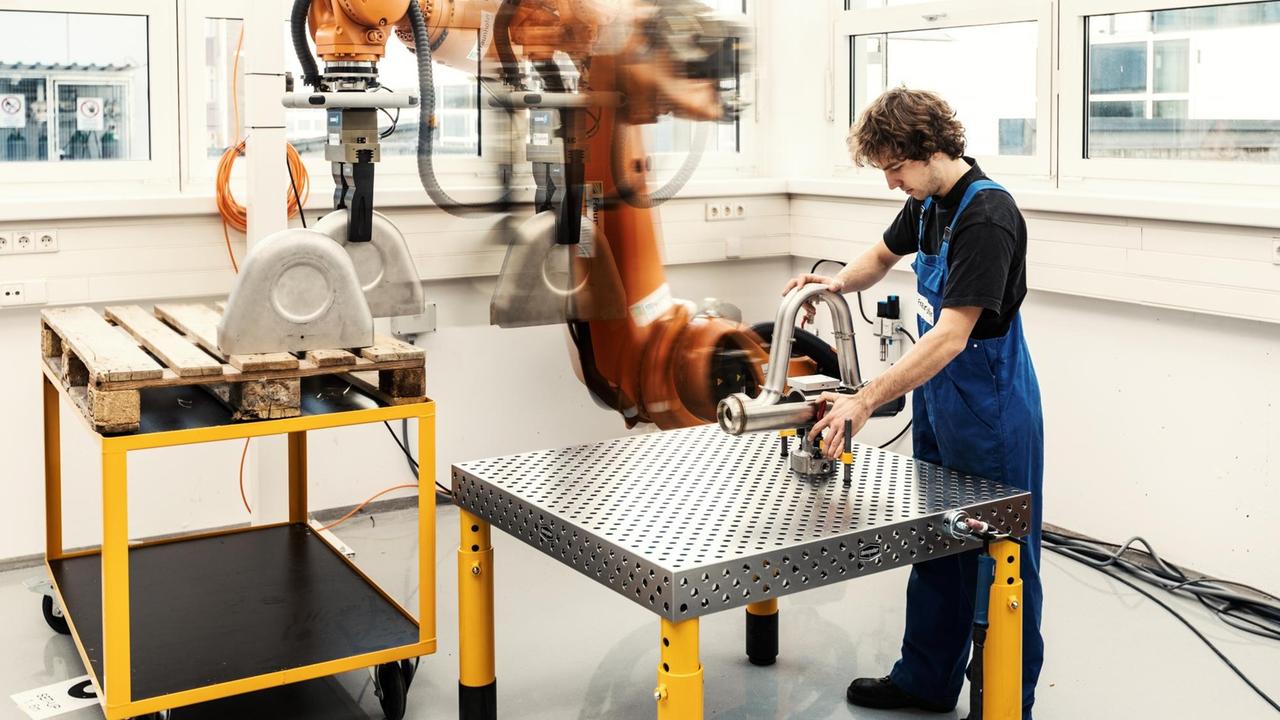 Mensch und Maschine arbeiten Hand in Hand: Der Industrieroboter im Future Work Lab in Stuttgart reicht dem Arbeiter ein Bauteil.