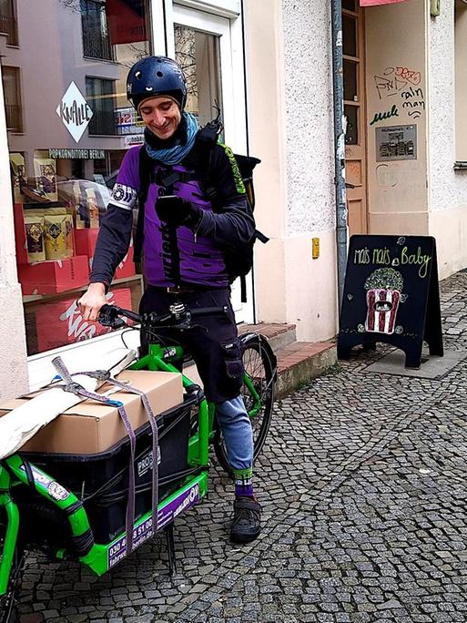 Fahrradkurier Simon Richter steht mit seinem Lastenrad auf einem Bürgersteig in Berlin.