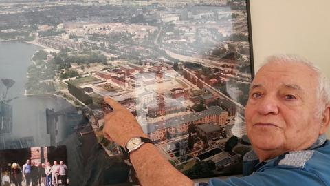 Horst Spörck vor einer Luftbildaufnahme von Rummelsburg – zu sehen die ehemalige Haftanstalt Rummelsburg, worauf er zeigt. Er war als Kind in den 30er und 40er Jahren im Großen Friedrichs-Waisenhaus in Rummelsburg.