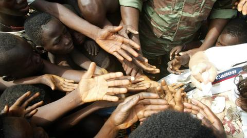 Erwachsene und Kinder strecken im Dorf Kotokpa in Benin ihre Hände aus wie in der Erwartung, etwas zu bekommen.