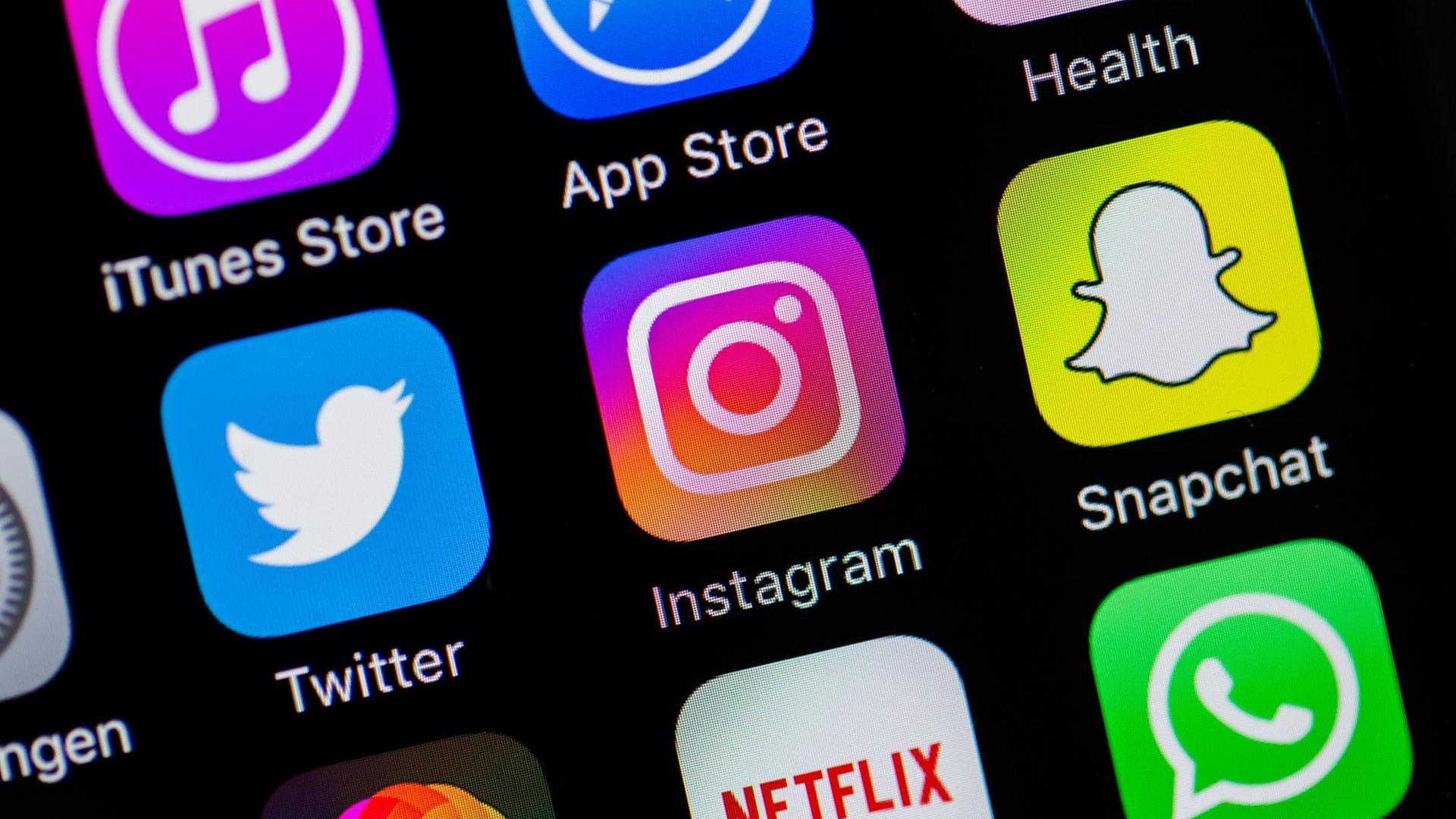 Auf einem Smartphone-Display sind die Logos von Twitter, Instagram und Snapchat zu sehen.