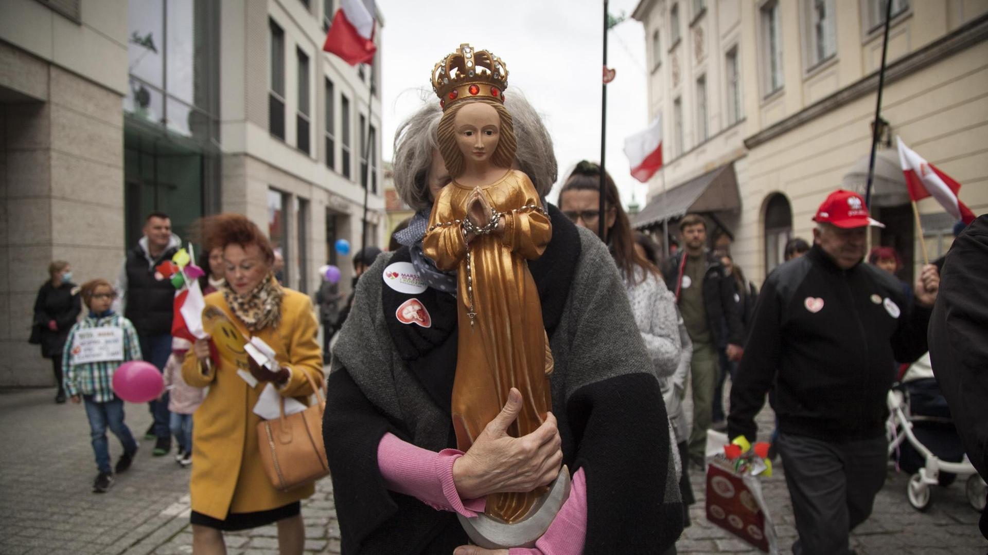 Eine Frau hält die Heilige Maria während des Nationalen Marsches für "Leben und Familie" vor ihr Gesicht, um für das traditionelle Verständnis der Ehe und des Lebens von der Empfängnis an zu demonstrieren.