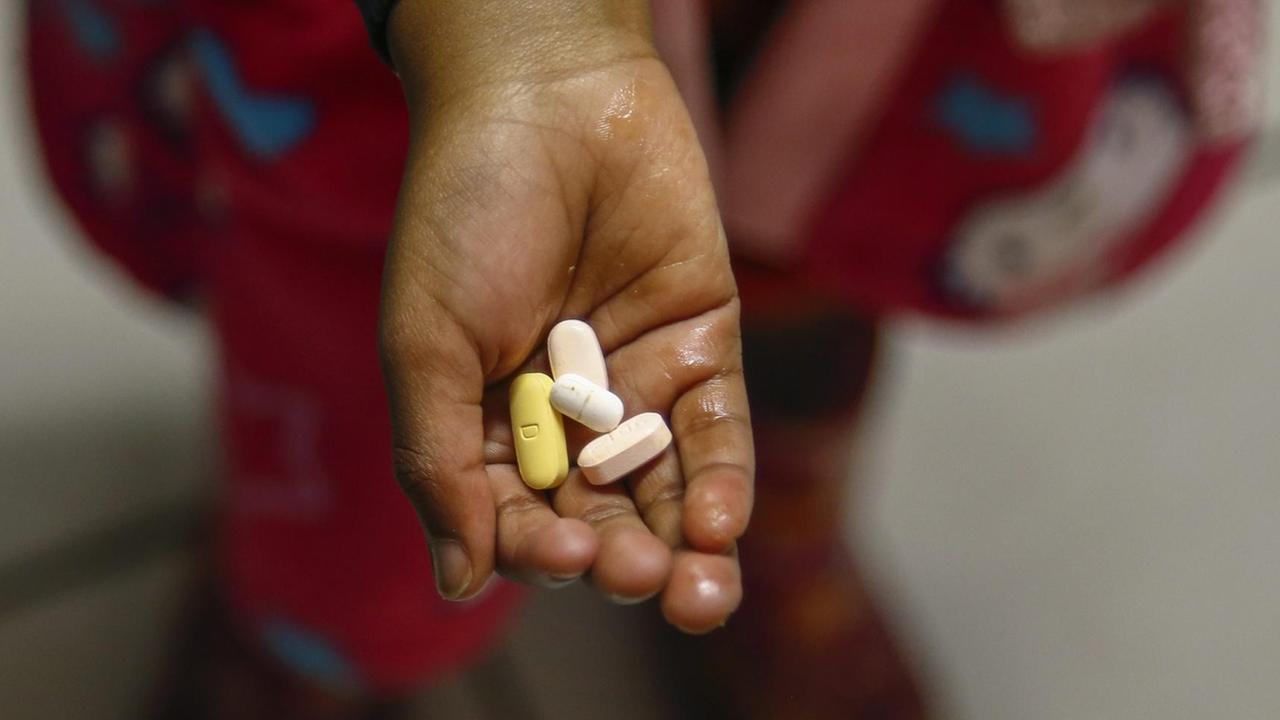 Ein südafrikanisches Kind hält antiretrovirale Medikamente in der Hand, mit der eine HIV-Infektion behandelt werden.