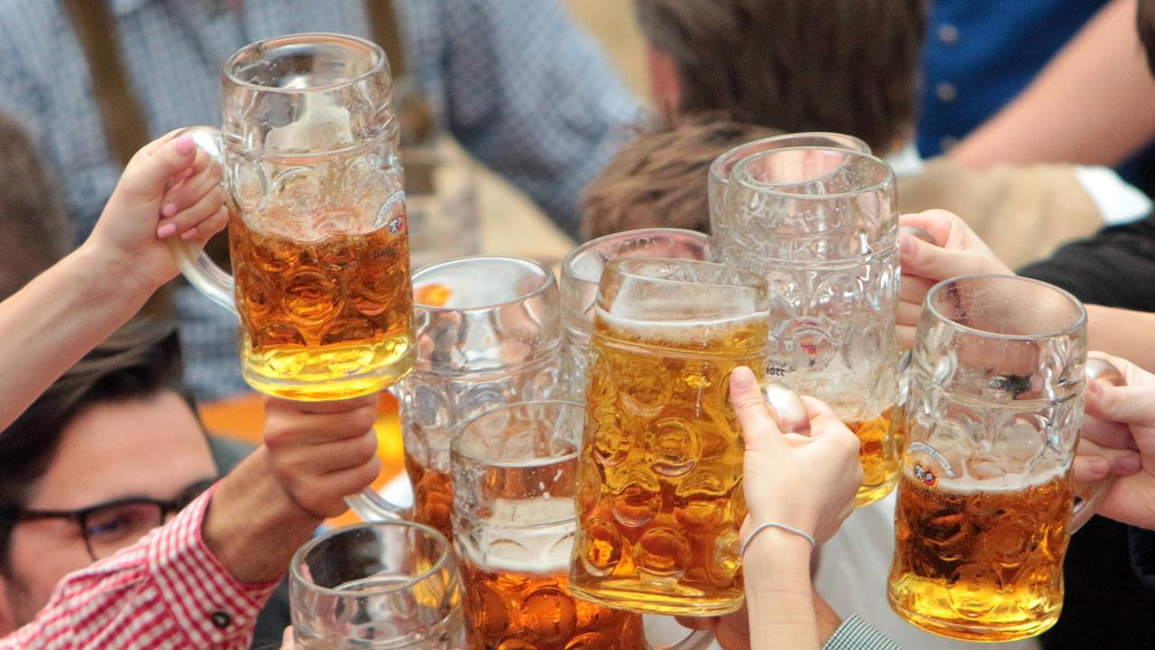 Mehrere Menschen stoßen auf dem Oktoberfest mit Biergläsern an