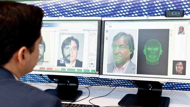 Ein Mann sitzt vor einem Computerbildschirm und arbeitet mit einem automatischen Gesichtserkennungssystem. file_source: Adrien Deneu / Safran