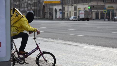 Ein Mann, der Essen in der russischen Hauptstadt Moskau ausliefert, wartet an einer Bushaltestelle.