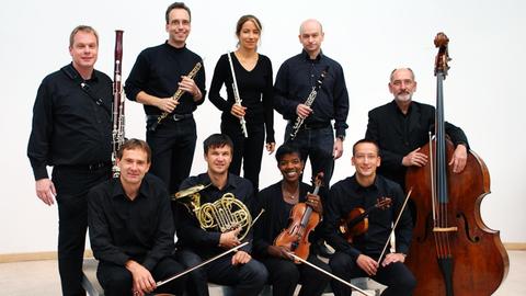 Polyphonia Ensemble Berlin posiert mit Intrumenten vor einer weißen Wand