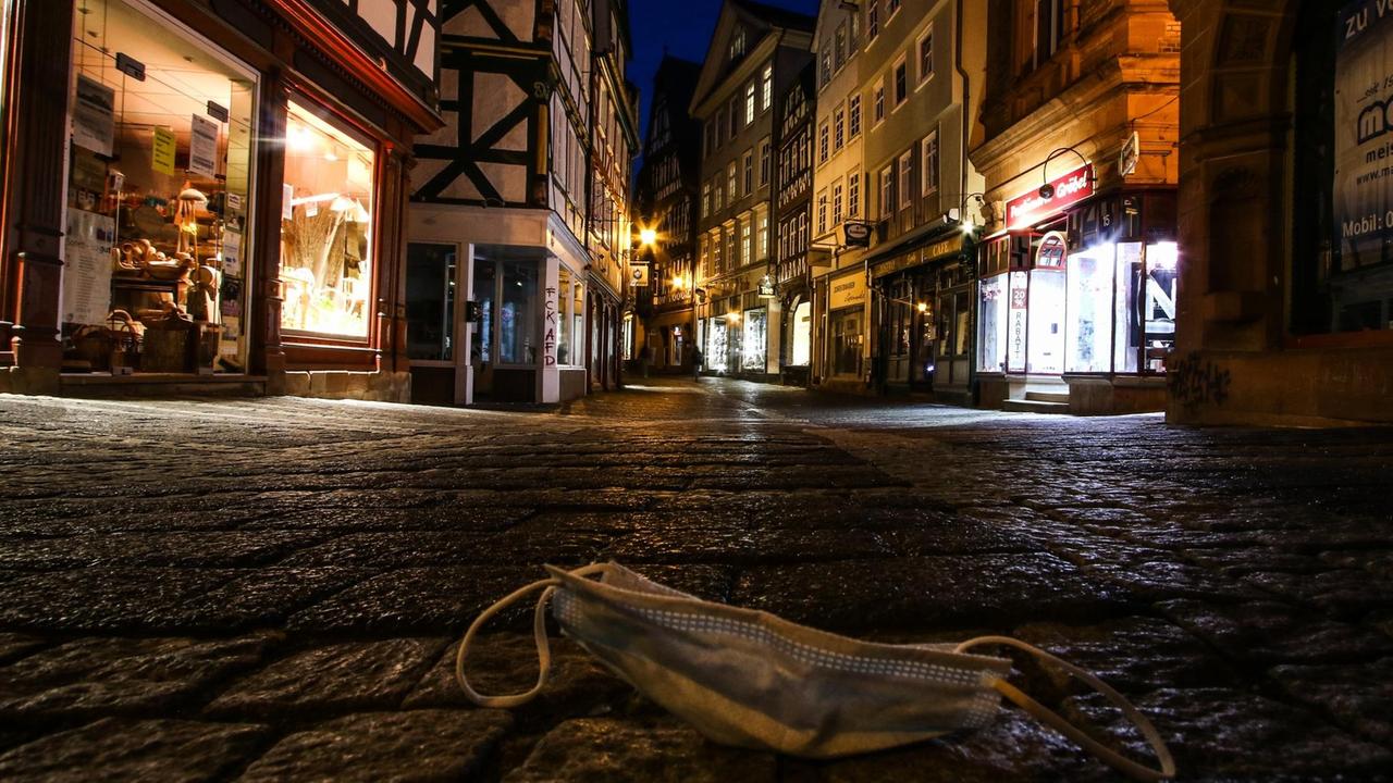 Ein Mund-Nasen-Schutz liegt auf der menschenleeren Straße in Marburgs Altstadt.