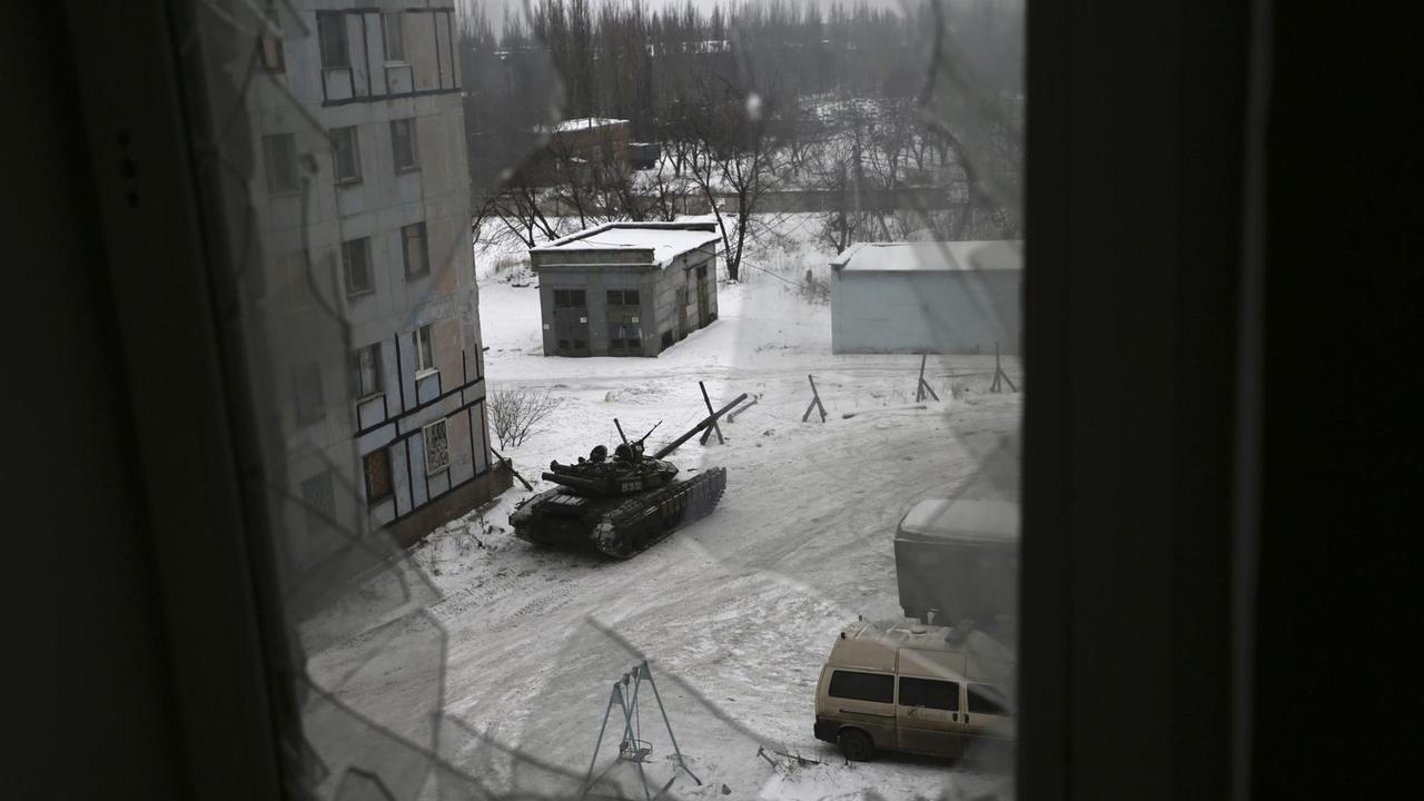 Blick durch ein zerstörtes Fenster auf einen Panzer der ukrainischen Armee in der Stadt Awdijiwka in der Ost-Ukraine.