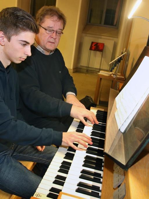 Diözesanmusikdirektor Gregor Frede (r) gibt am 07.12.2017 in der Kirche des Juliusspitals in Würzburg (Bayern) dem 17-jährigen Michael Netrval Unterricht an der Orgel.
