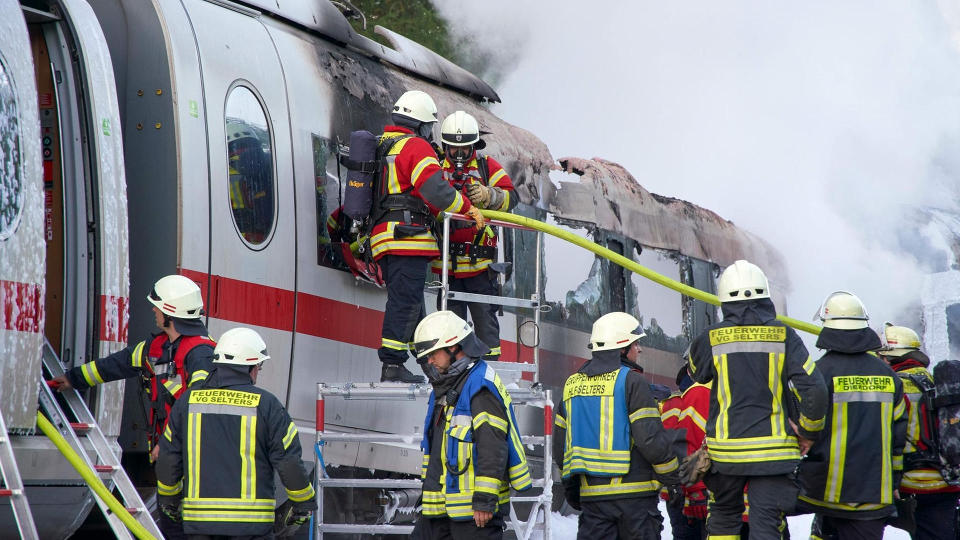 Feuerwehrleute löschen einen brennenden ICE-Wagen, der auf der Schnellstrecke zwischen Frankfurt und Köln Feuer gefangen hatte.