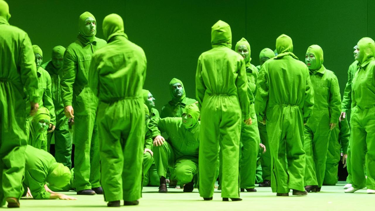 Hier zu sehen: der Chor der Oper Bonn, komplett in grünen Overalls. Auch die Gesichter sind grün bemalt.