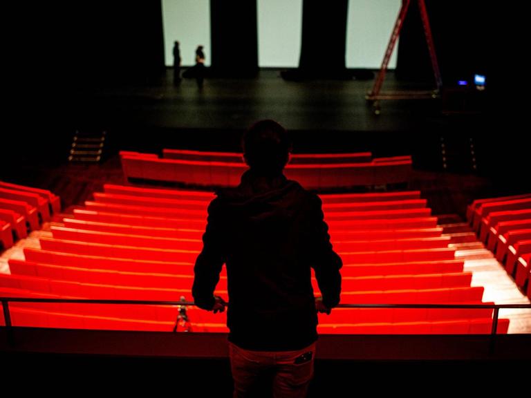 Ein Mensch blickt in ein leeres Theater.