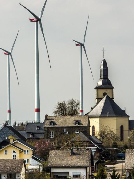 Der Ort Mörsdorf im Rhein-Hunsrück-Kreis mit der katholischen Kirche und hinter dem Ort fünf Windenergieanlagen.