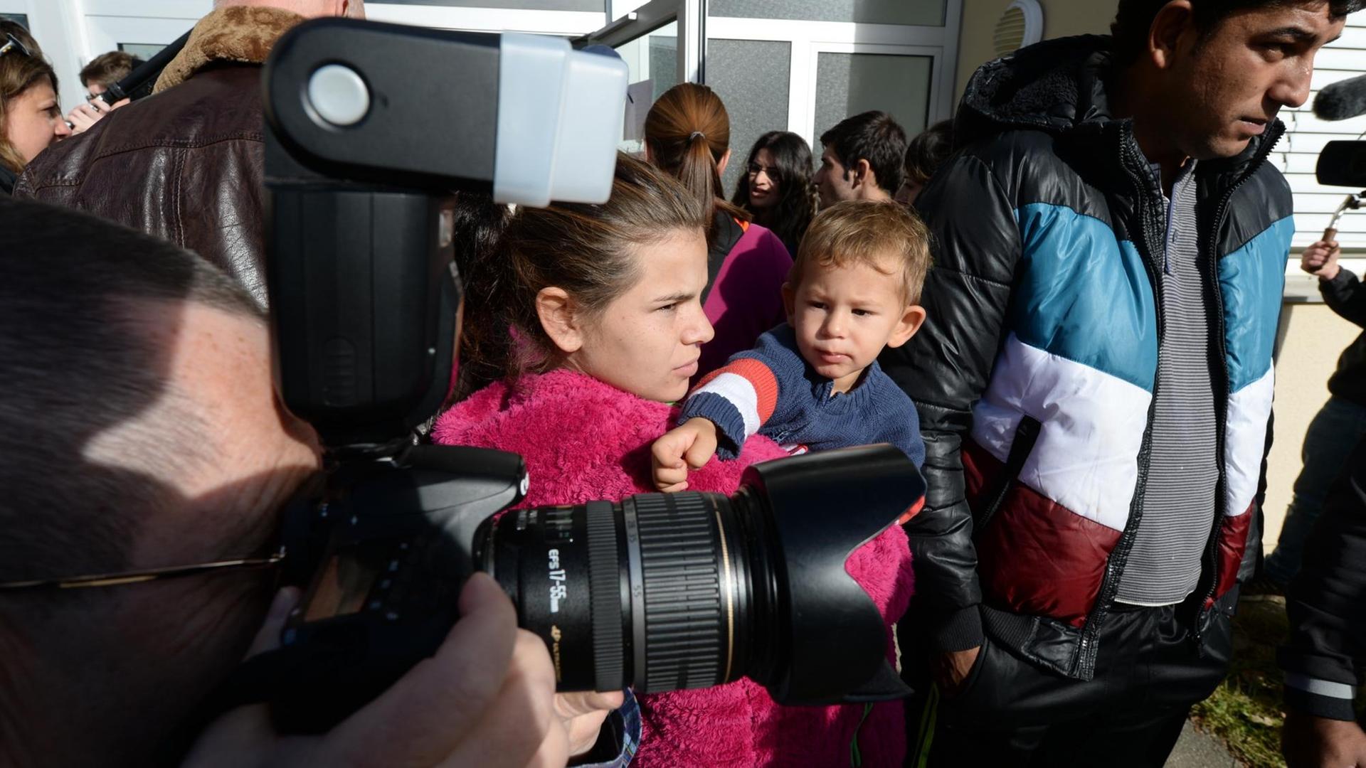 Mehrere Asylbewerber werden von Kamerateams und Fotografen umlagert.