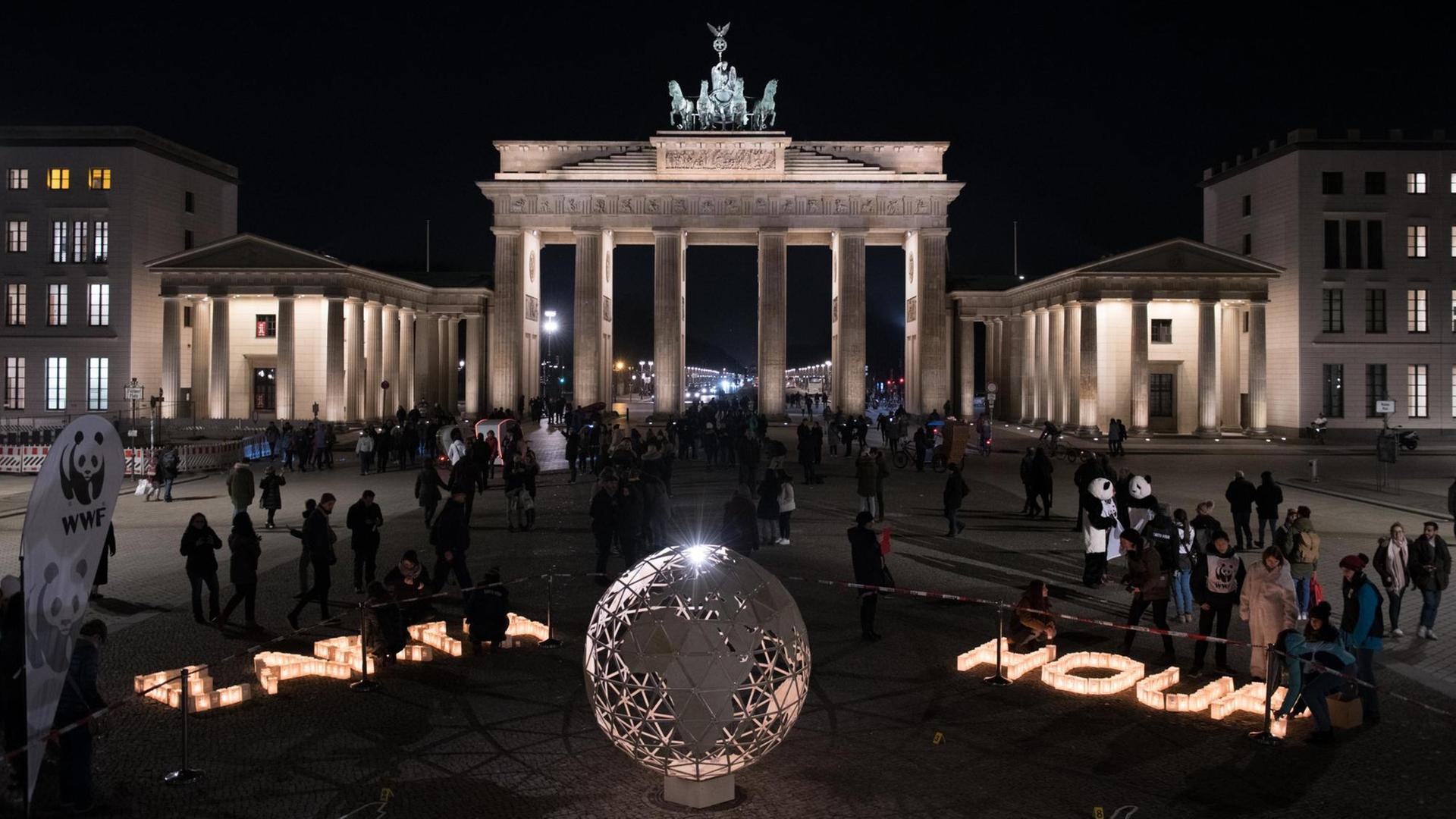 Am Brandenburger Tor in Berlin steht eine leuchtende Weltkugel und die Worte "Earth Hour" sind zu sehen.