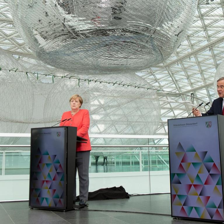 Nordrhein-Westfalen, Düsseldorf: Bundeskanzlerin Angela Merkel (CDU) und Armin Laschet (CDU), Ministerpräsident von Nordrhein-Westfalen, sprechen bei einer Pressekonferenz.