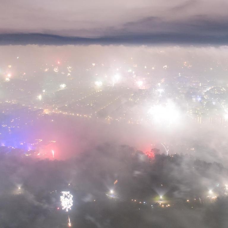 Feuerwerksraketen explodieren in der Silvesternacht über München und hüllen die Innenstadt in dichten Rauch