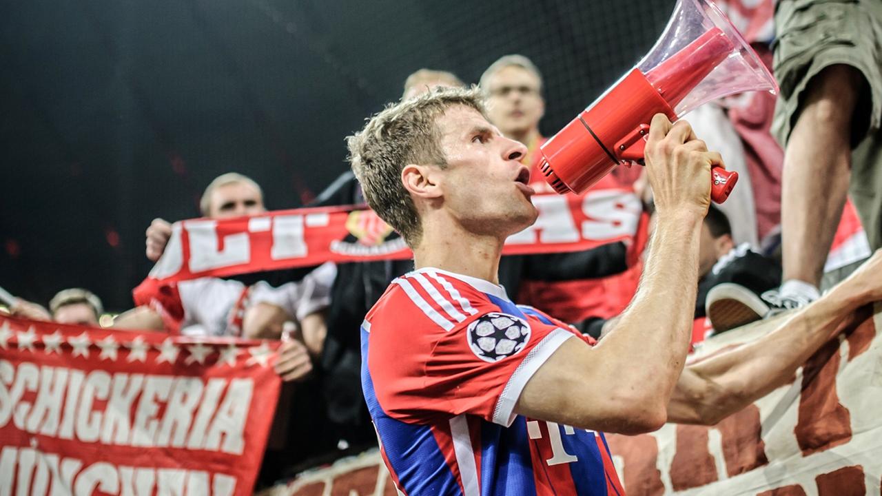 Münchens Spieler Thomas Müller steht in der Allianz-Arena in München am Zaun zum Fanblock. Nach dem Sieg gegen Porto animiert er die Zuschauer mit einem Megaphon zu Sprechchören.