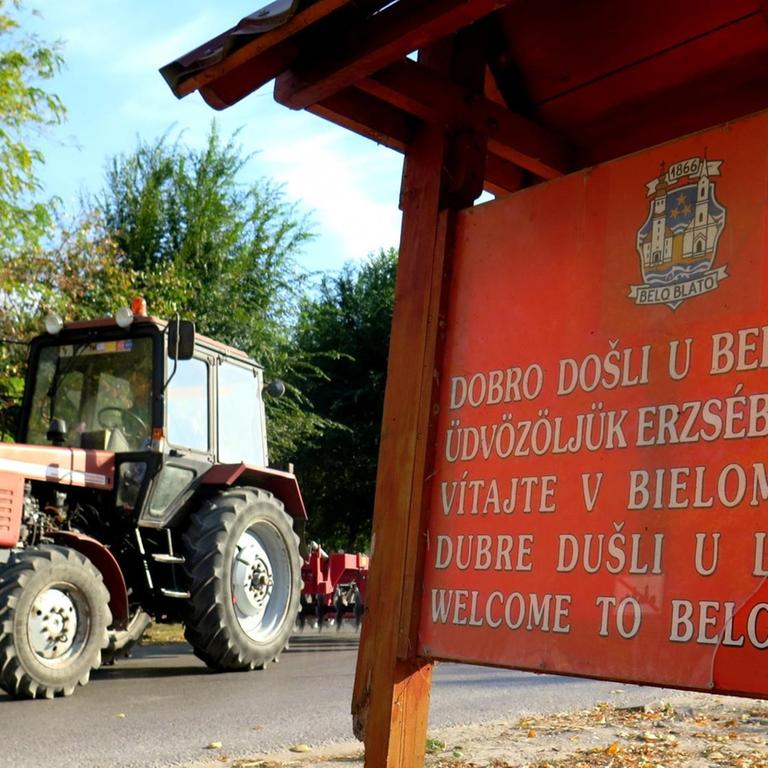 Ein Ortsschild in verschiedenen Sprachen steht am Ortseingang von Belo Bato