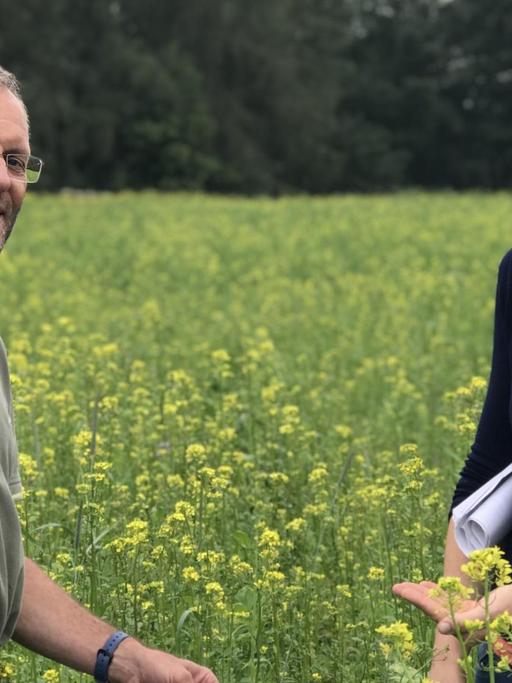 Die Landwirtin Cornelia Briem-Grooten steht zusammen mit dem Berater Georg Milz von der Landwirtschaftskammer NRW in einem blühenden Feld.
