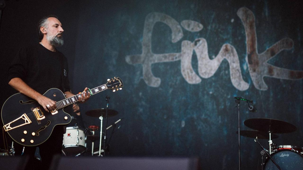 Ein Mann steht mit einer Gitarre auf der Bühne.
