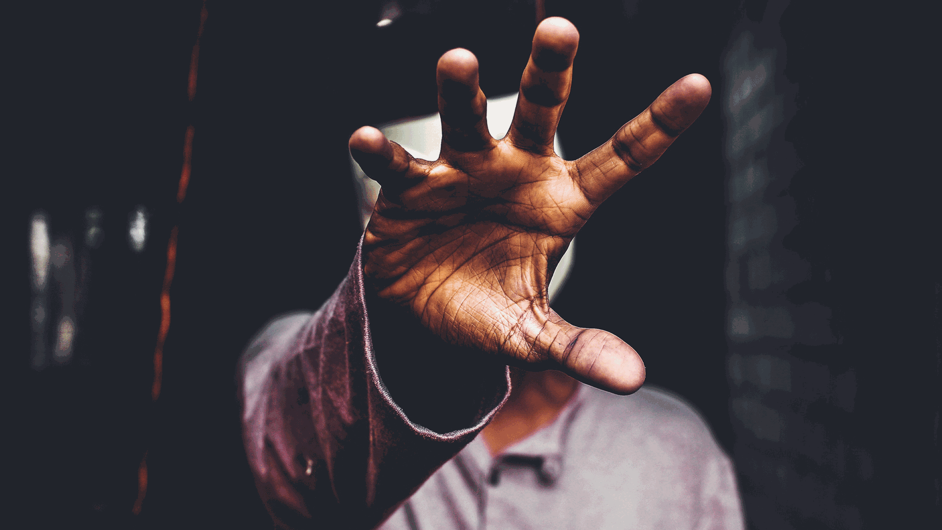 Ein schwarzer Mann hält seine geöffnete Hand vor sein Gesicht.