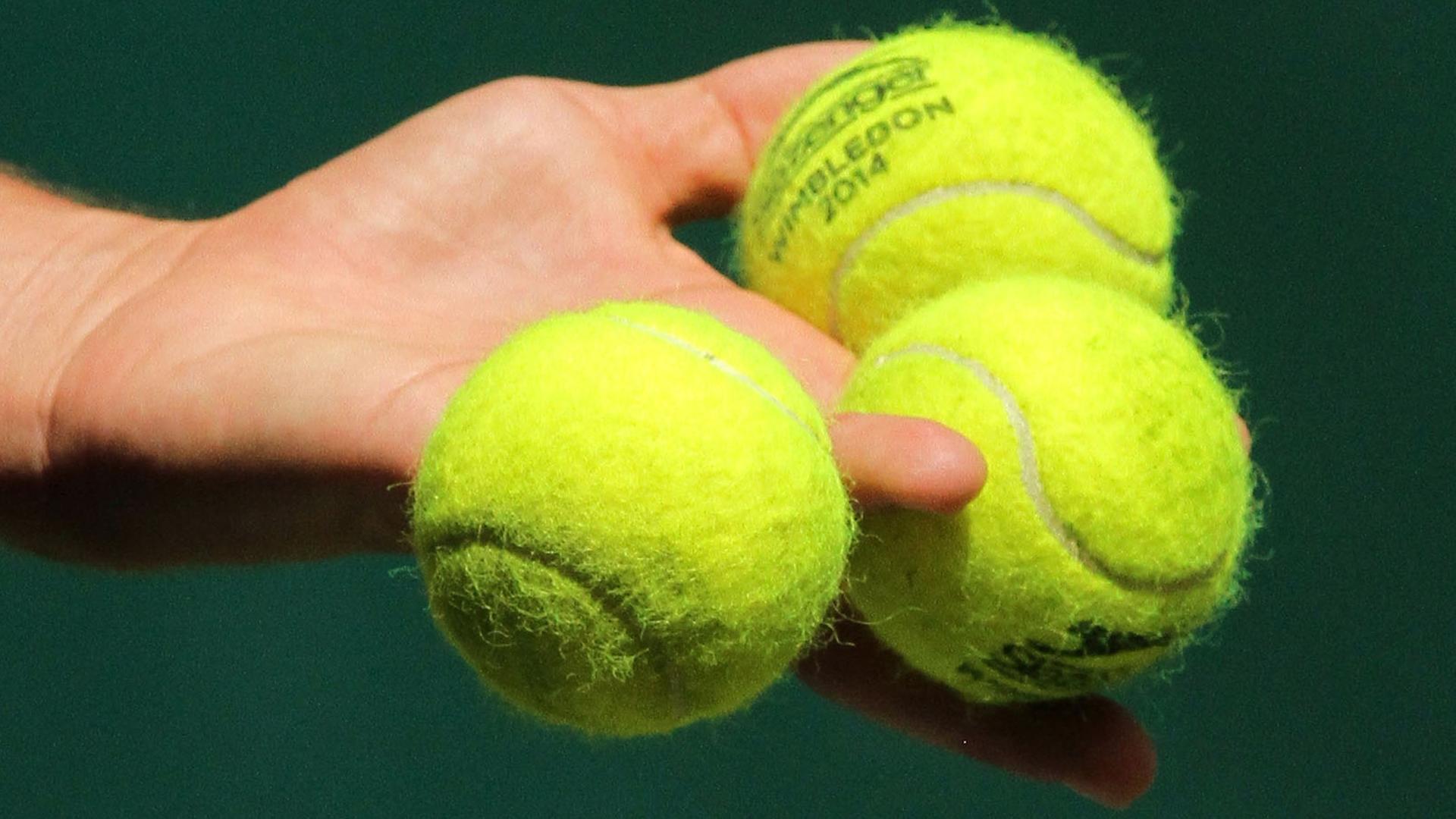 Drei Tennisbälle in der Hand einer Spielerin