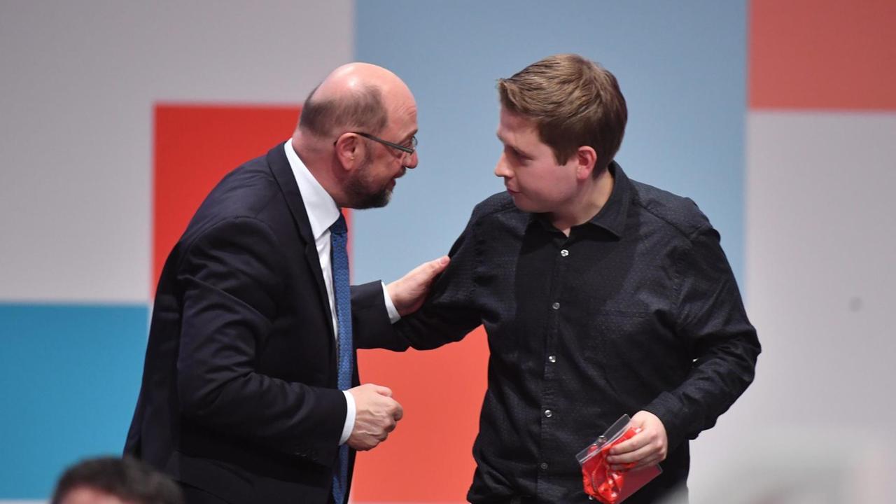 Der Juso-Vorsitzende Kevin Kühnert (r) gibt dem Parteivorsitzenden Martin Schulz die Hand nach den Abstimmungen über verschiedene Anträge zu Sondierungsgesprächen für eine große Koalition.