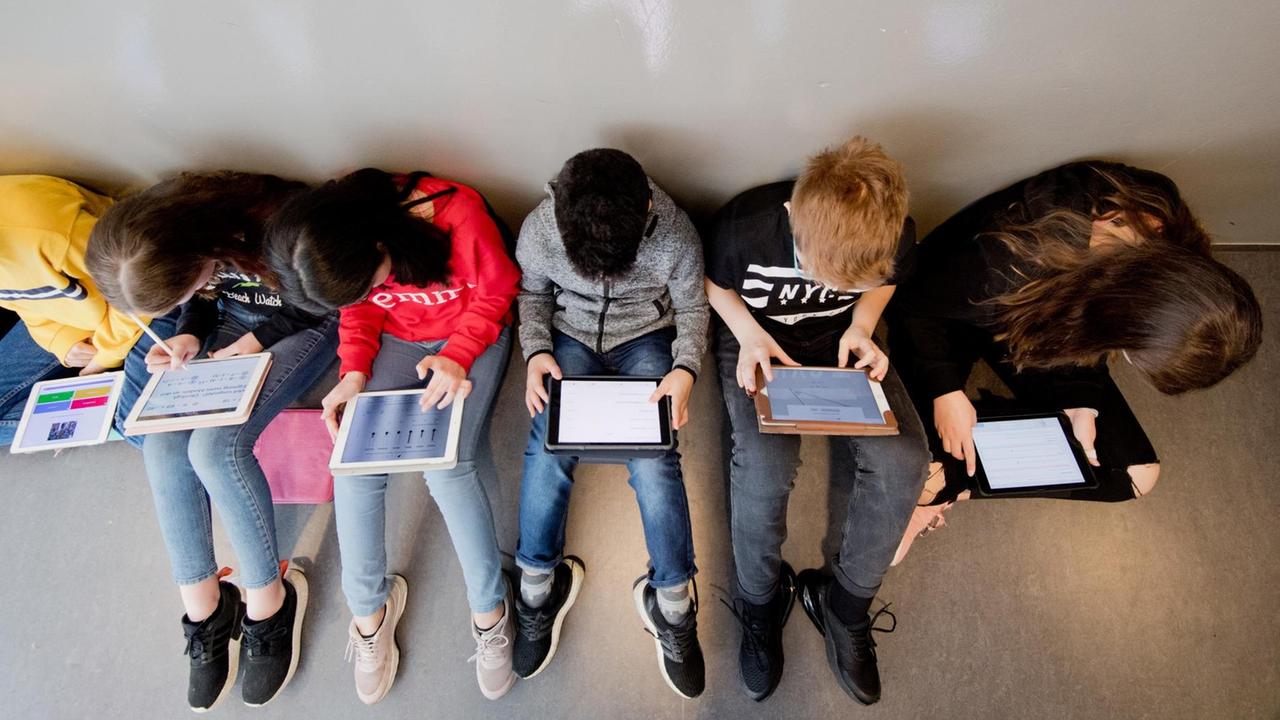 Schülerinnen und Schüler einer 7. Klasse lernen mit iPads im Matheunterricht an der Oberschule Gehrden in der Region Hannover. Mehrere Jugendliche sitzen auf dem Boden.